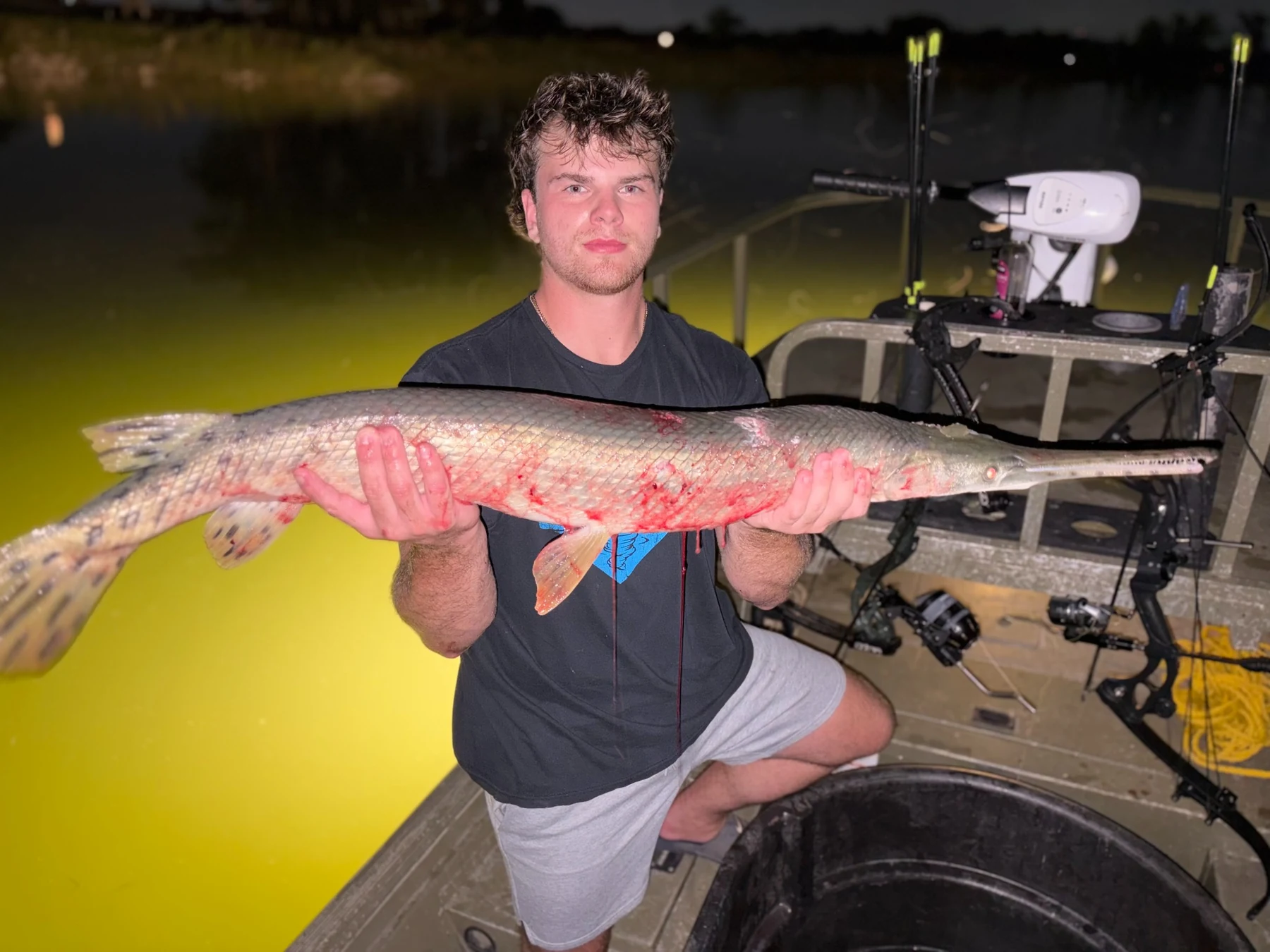 Jacob holding a large gar while fishing at night